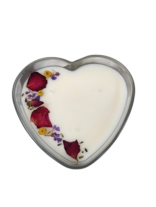 13oz Heart-shaped clear glass candle with 3 wicks embellished with rose petals and other botanicals along the left side of the heart.