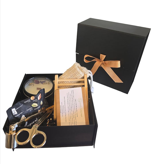 Medium-sized black boxed gift set with nuts, a shiny gold candle care set of a snuffer, dipper and wick trimmer with a boxed natural soap, soap loofah pouch and wooden soap saver with an 8oz black tin candle by CandleLux.