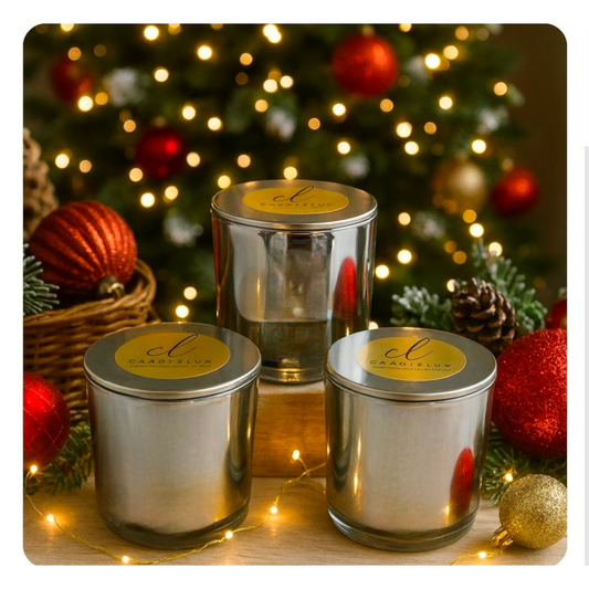 Three silver luxury candles by CandleLux displayed on a table in a festive holiday setting with ornaments and Christmas lights